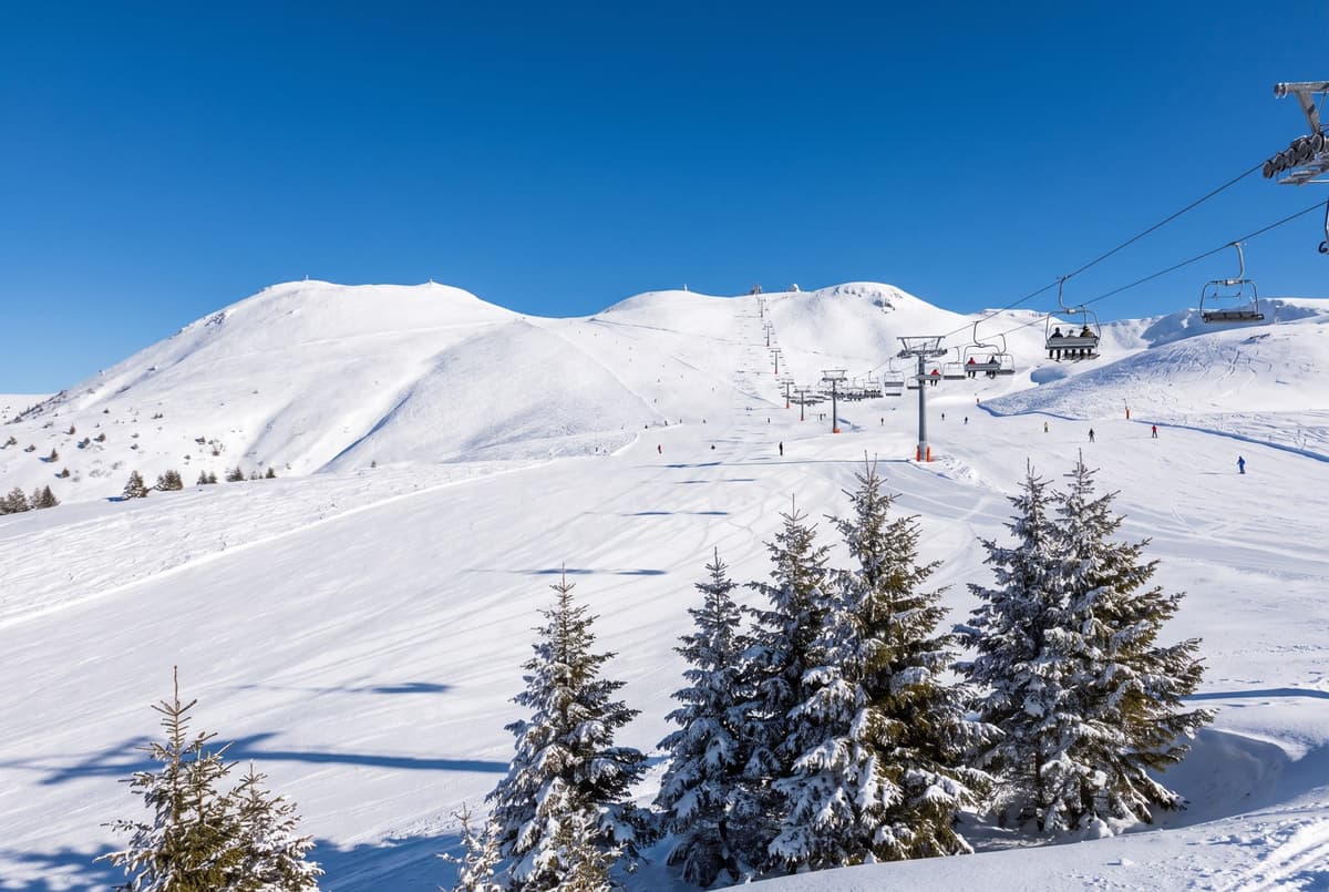 Pistes enneigées et télésiège de la station de Super-Besse sous un ciel bleu